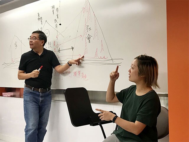 While Senior Lecturer Mr Li Chin-wa (left) teaches, Cat (right), the interpreter, tries her best to convert everything into sign language, providing Brenda with equal access to higher education.