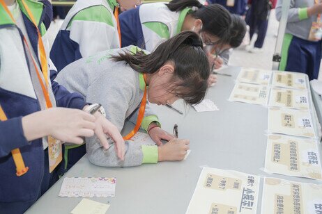 参与活动的小学生在摊位游戏前写下希望感谢的人与事